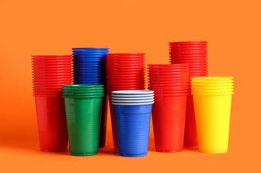 Turuncu arka planda birçok renkli plastik bardak