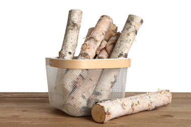 Tahta sepetin üzerinde ağaç kütükleri beyaz arka planda.