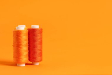 Turuncu arkaplanda iplik makaraları