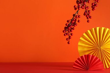 Turuncu arka planda ağaç dalı olan Çin kağıt vantilatörleri.