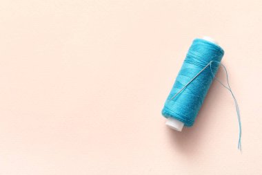 Bej arka planda iğnesi olan mavi dikiş ipliği