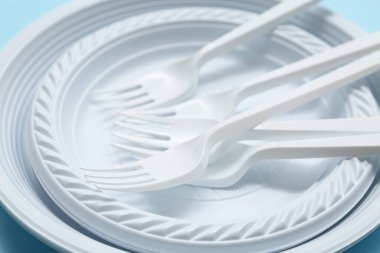 Mavi arkaplanda plastik sofra takımı ve çatal bıçak takımı, yakın plan