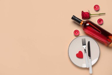 Sevgililer Günü için güzel bir masa, mumlar, bir şişe şarap ve bej arka planda gül çiçeği.