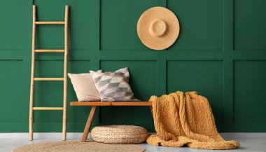 Yastıklı ahşap bank, ekose ve merdiven yeşil duvarın yanında.