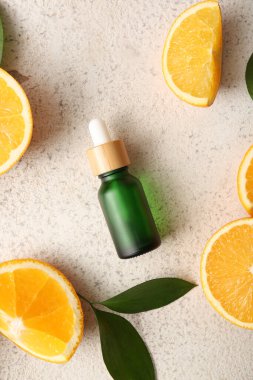 Beyaz zemin üzerinde taze meyve ve yapraklar olan bir şişe portakal yağı.