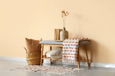 Çimenli vazo, kitap ve ekose bej duvarın yanındaki odada.