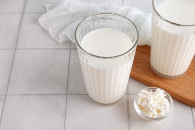 Taze kefir bardakları ve beyaz fayanslı süzme peynirli kase, yakın plan.