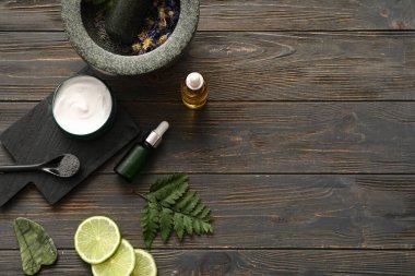 Koyu ahşap arka planda doğal kozmetik malzemeleri ve tokmağı olan havan topu.