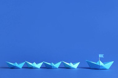 Diğerlerinin yanında bayraklı Origami teknesi. Liderlik kavramı