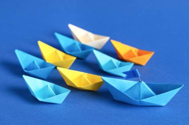 Biri bayraklı bir origami teknesi, diğeri mavi arka planda.