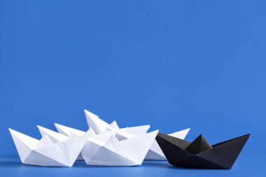 Mavi arka planda beyaz olanlar arasında siyah origami teknesi