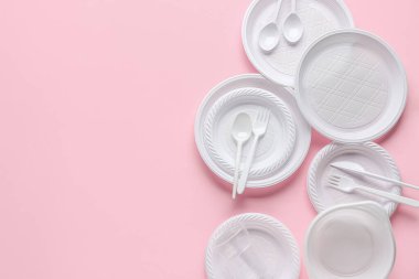 Pembe arka planda plastik tabaklar, fincanlar ve çatal bıçak takımı