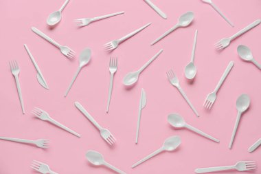Pembe arka planda plastik çatallar ve kaşıklar