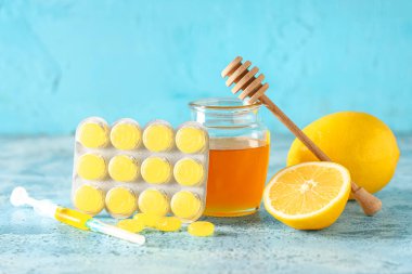 Limonlu öksürük damlası, bal kavanozu ve mavi grunge arka planda şırınga.