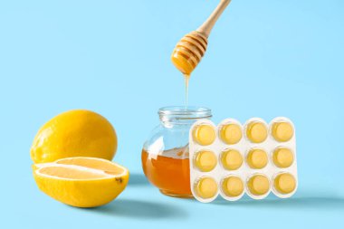 Öksürük damlaları mavi arka planda ballı, limonlu ve bal dolu.