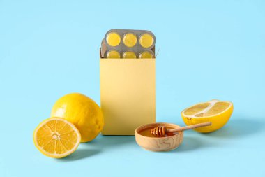 Limonlu öksürük damlası ve mavi arka planda bir kase bal.