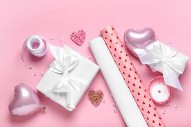 Hediye kutuları, ambalaj kağıtları ve pembe arka planda kalpler. Sevgililer Günü kutlaması