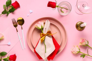 Gül çiçekleri, mum ve pembe arka planda zarfla Sevgililer Günü için güzel bir masa.