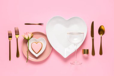 Sevgililer Günü için güzel bir masa, lezzetli kurabiyeler ve pembe arka planda gül çiçekleri.