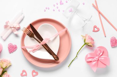 Gül çiçekleri, mumlar ve beyaz arka planda hediye kutusuyla Sevgililer Günü için masa ayarı