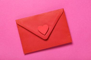 Pembe arka planda güzel kırmızı bir zarf, yakın plan. Sevgililer Günü kutlaması