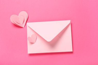 Kırmızı zarflı kompozisyon ve pembe arka planda kağıt kalpler. Sevgililer Günü kutlaması