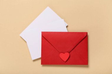 Kırmızı zarflı kompozisyon ve bej arka planda boş kartlar. Sevgililer Günü kutlaması