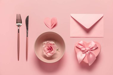 Gül çiçeği, zarf ve pembe arka planda hediye kutusuyla Sevgililer Günü için güzel bir masa.