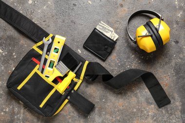 Cüzdanında para ve inşaatçının alet çantası var.