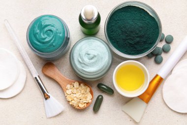 Kavanozlar dolusu spirulina yüz maskesi ve bej rengi grunge arka plan malzemeleri, yakın plan.