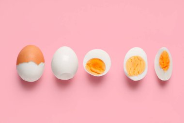 Pembe arka planda bir sıra taze haşlanmış yumurta.