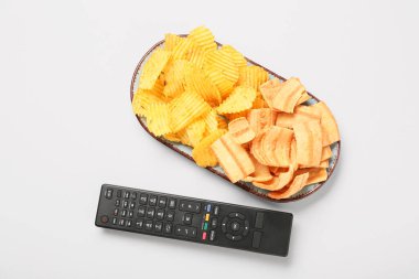 Modern TV uzaktan kumandası ve gri arka planda patates cipsi tabağı