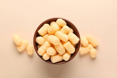 Bej arka planda mısır çubukları olan bir kase.