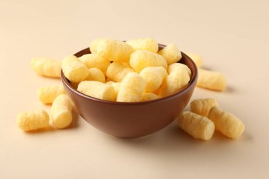 Bej arka planda mısır çubukları olan bir kase.