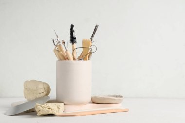 Beyaz masa üzerinde kil ve heykel aletleri seti olan tutucu