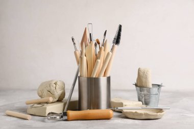 Beyaz grunge masa üzerinde kil ve heykel araçları seti ile tutucu