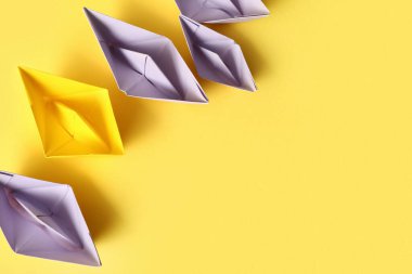Sarı arka planda farklı kağıt tekneler