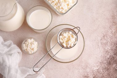 Bir bardak taze kefir ve beyaz arka planda süzme peynirli kâseler.