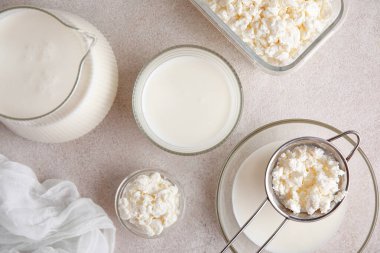 Bir bardak taze kefir ve beyaz arka planda süzme peynirli kâseler.