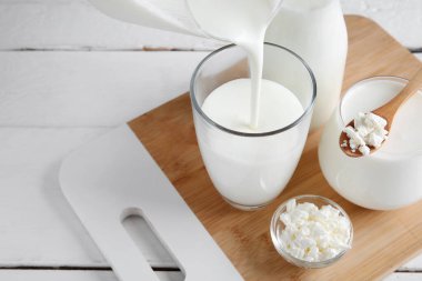 Sürahiden bardaklara beyaz ahşap arka planda kefir dök