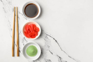 Beyaz arka planda wasabi, soya sosu ve zencefil turşusu olan kaseler.