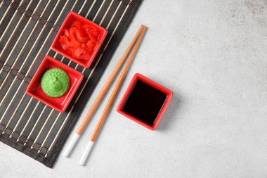 Beyaz arka planda wasabi, soya sosu ve bambu hasırı üzerinde zencefil turşusu.