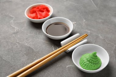 Wasabi, soya sosu ve gri arka planda zencefil turşusu, yakın plan.