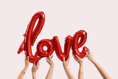 Beyaz arka planda balondan yapılmış aşk sözcüğü olan kadın elleri. Sevgililer Günü kutlaması