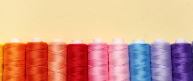 Bej arkaplanda renkli iplik makaraları, üst görünüm