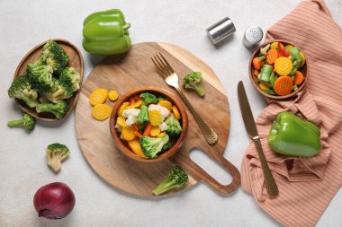 Tabak ve kâselerle karışık sebzeler ve hafif arka planda çatal bıçak.