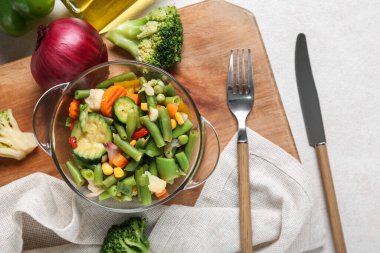 Hafif arka planda haşlanmış karışık sebze ve çatal bıçaklı kase.