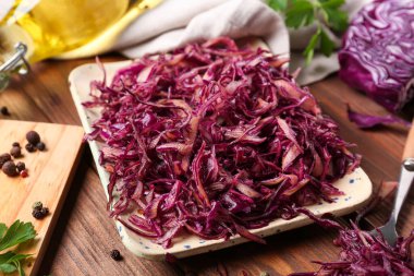 Lezzetli kırmızı lahana turşulu tabak ve ahşap zemin üzerinde biber.