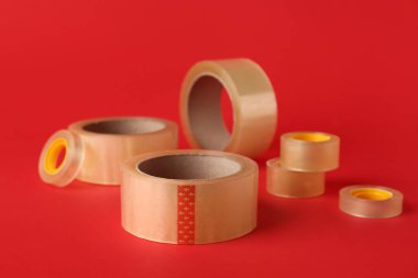 Kırmızı arkaplanda birçok yapışkan bant ruloları