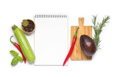 Beyaz arkaplanda boş tarif kitabı, şifalı bitkiler ve taze sebzeler bulunan kompozisyon